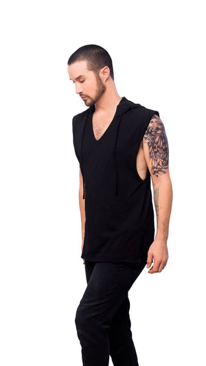 A person wearing a black Apollo Tank top with a V-neck cut and wide shoulders. The individual is also wearing dark pants and has tattoos on the arms.