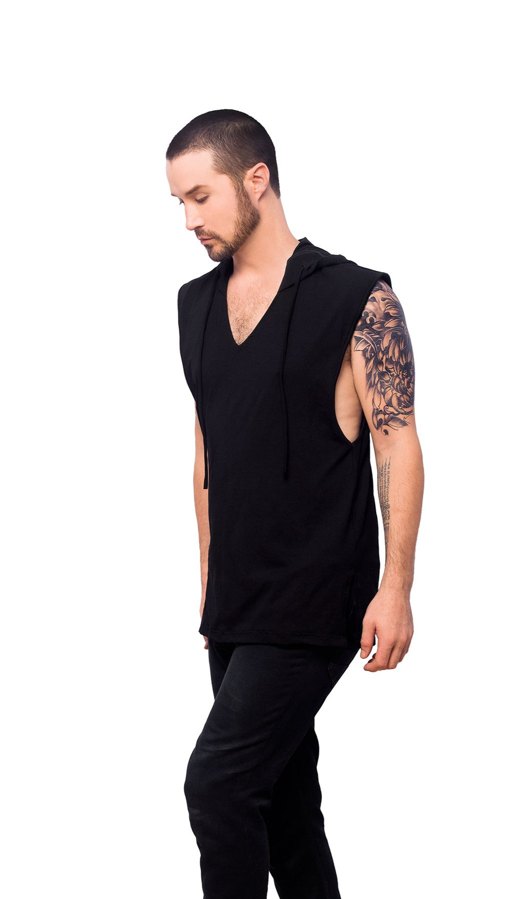 A person wearing a black Apollo Tank top with a V-neck cut and wide shoulders. The individual is also wearing dark pants and has tattoos on the arms.